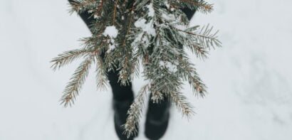 Girl standing in the snow holding fir tree branches