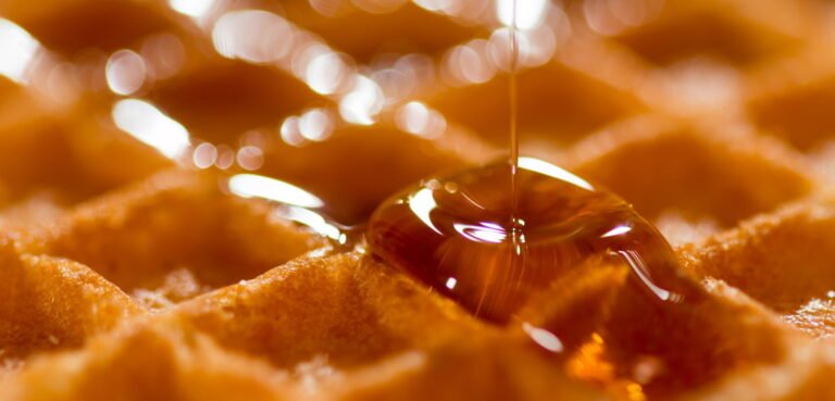 Maple syrup poured onto a waffle